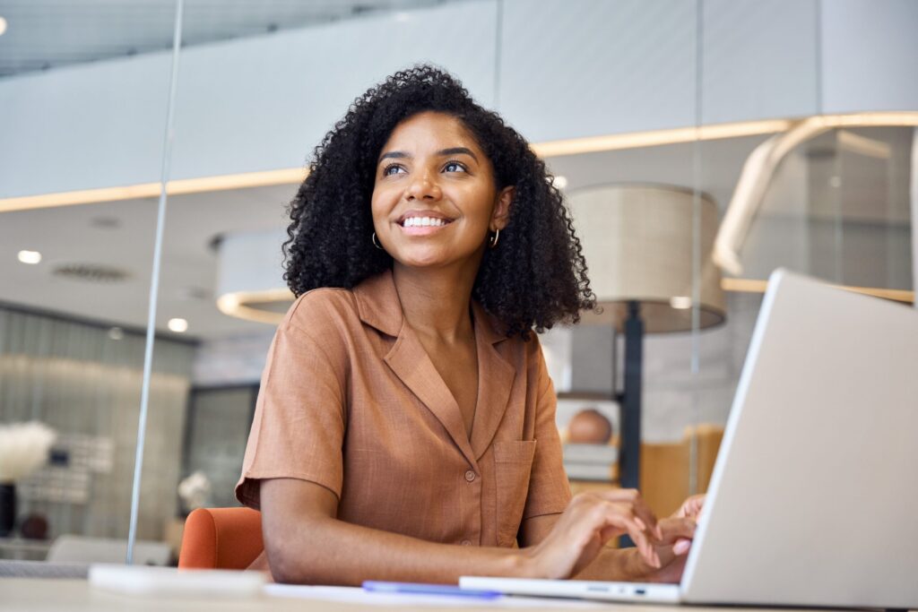 Smiling woman typing her professional development goals on her laptop